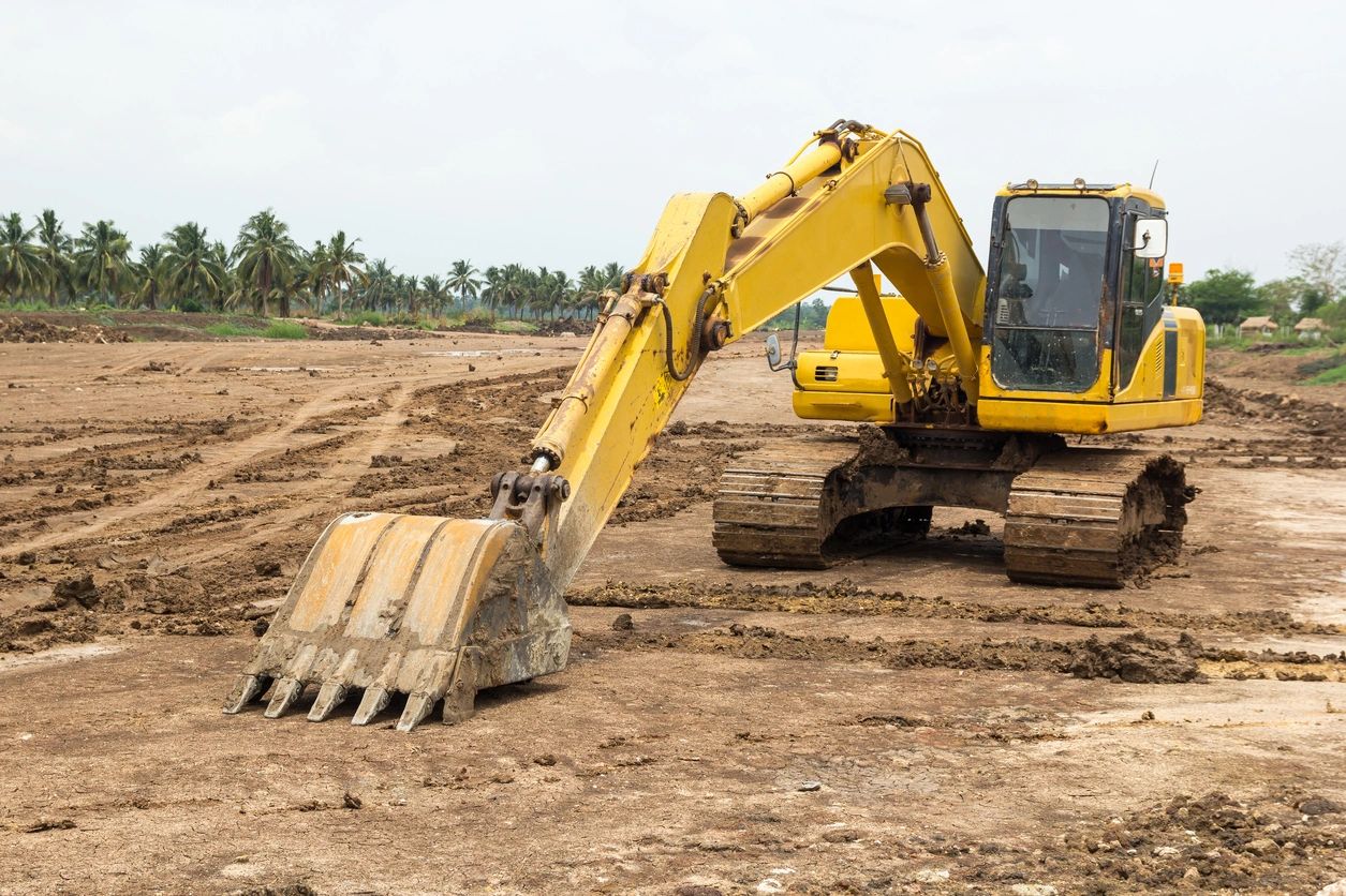 Yellow excavator on a construction site with muddy terrain.
